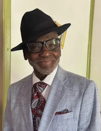 Smiling man in gray suit and black hat