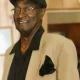 Smiling man in beige blazer and cap