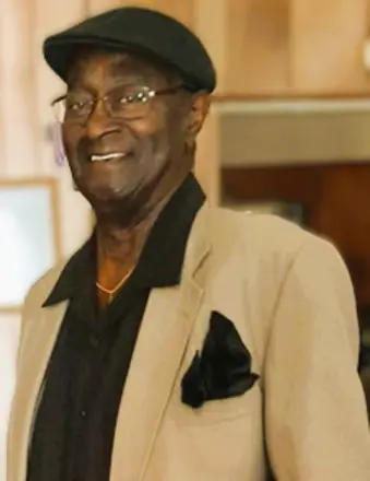 Smiling man in beige blazer and cap