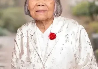 Elderly woman in floral jacket with red flower