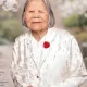 Elderly woman in floral jacket with red flower