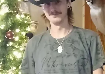 Man in cowboy hat by Christmas tree