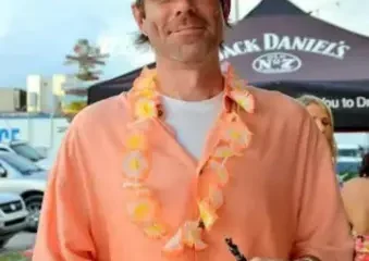 Man in orange shirt with lei holding drink