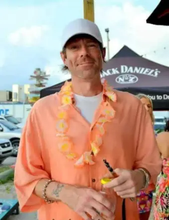 Man in orange shirt with lei holding drink