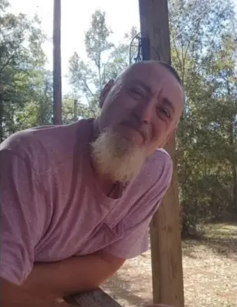 Man with white goatee leaning on porch