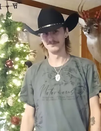 Man in cowboy hat by Christmas tree