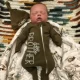 Sleeping newborn in green 'little brother' onesie