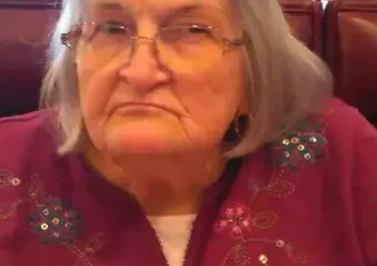 Elderly woman with glasses sitting in restaurant booth