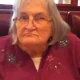 Elderly woman with glasses sitting in restaurant booth