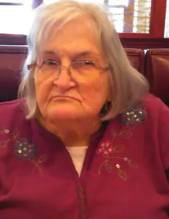 Elderly woman with glasses sitting in restaurant booth