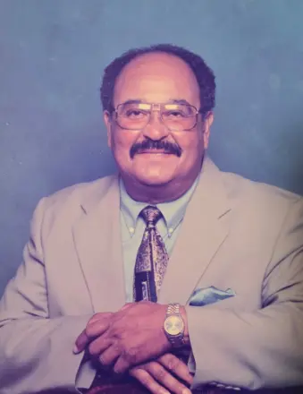 Man in beige suit with glasses smiling