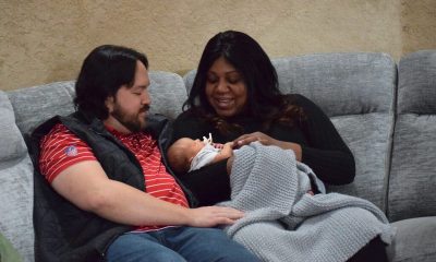 Couple holding newborn baby on couch