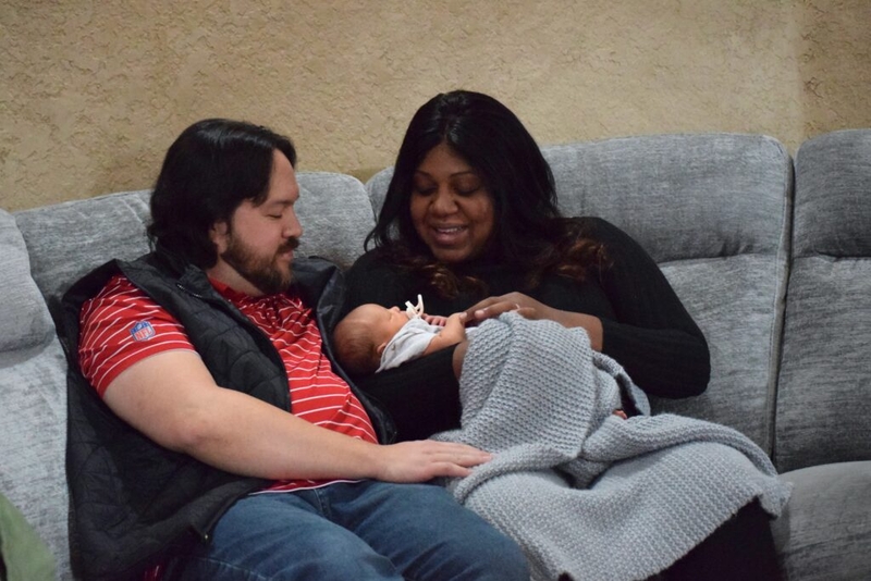 Couple holding newborn baby on couch