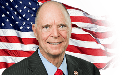 Older man in suit before American flag