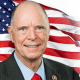 Older man in suit before American flag