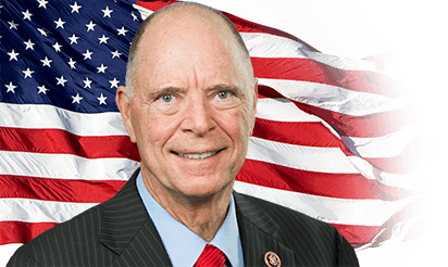 Older man in suit before American flag