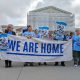 Protesters holding 'We Are Home' banner outside court