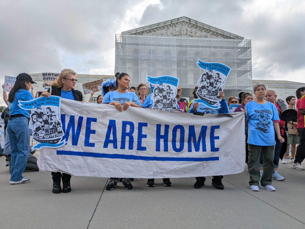 Protesters holding 'We Are Home' banner outside court