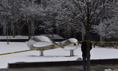 Snow-covered sculpture cordoned with caution tape outdoors