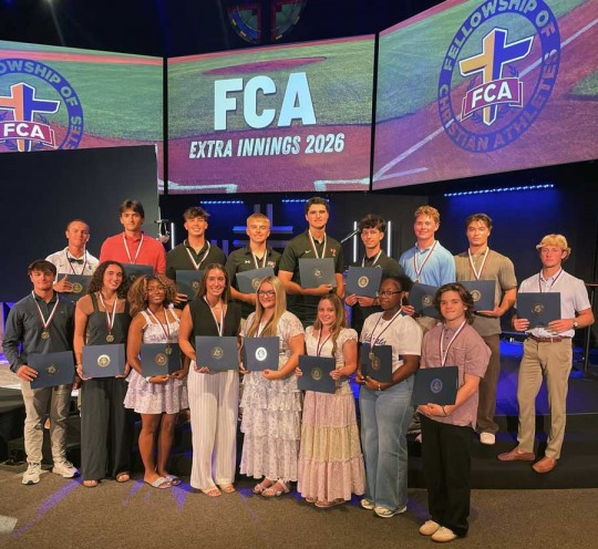Students holding certificates on FCA stage event