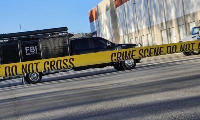 FBI vehicle behind crime scene tape outside warehouse