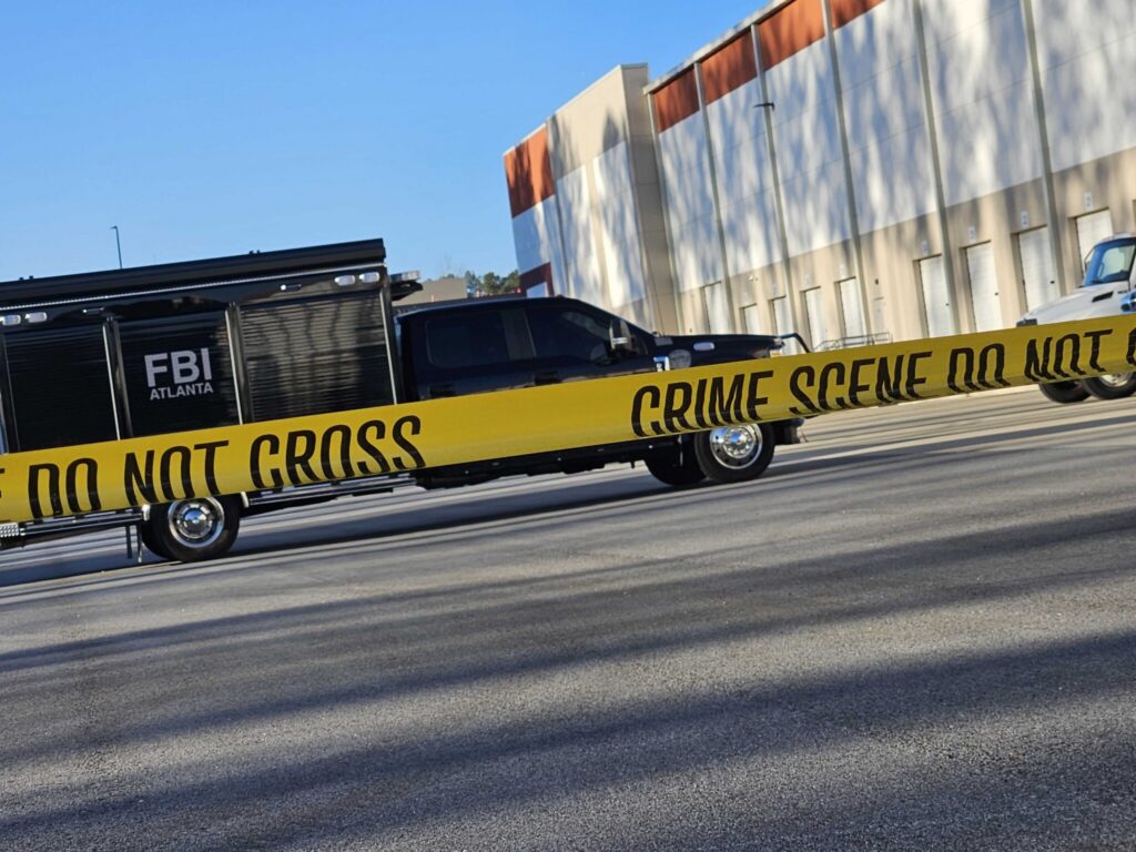 FBI vehicle behind crime scene tape outside warehouse