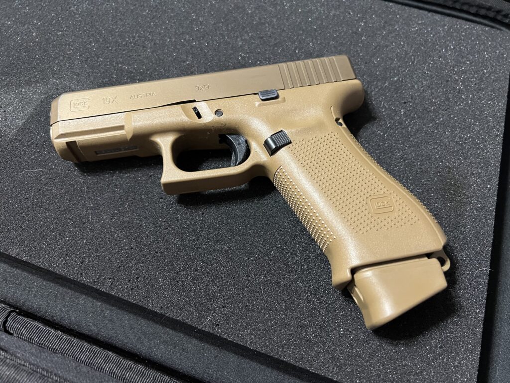 Tan Glock 19X pistol on black surface