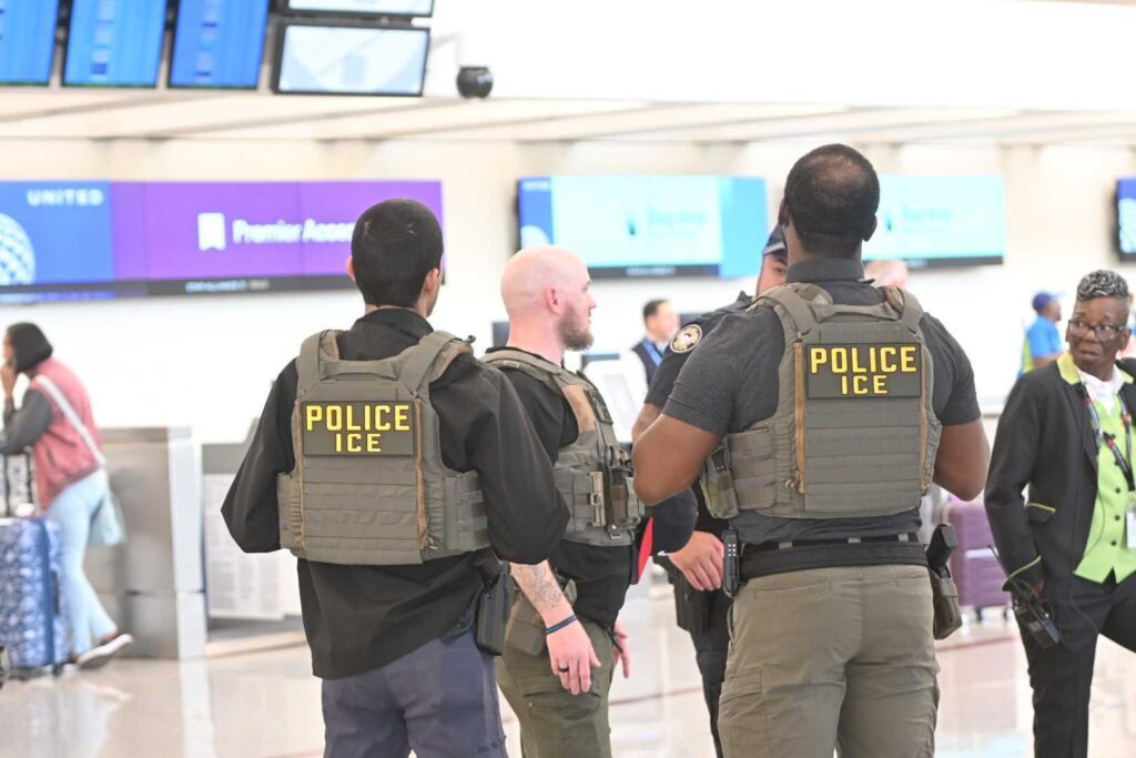 ICE police officers standing in airport terminal