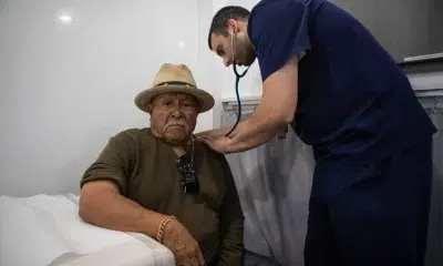 Doctor examining elderly patient with stethoscope in clinic