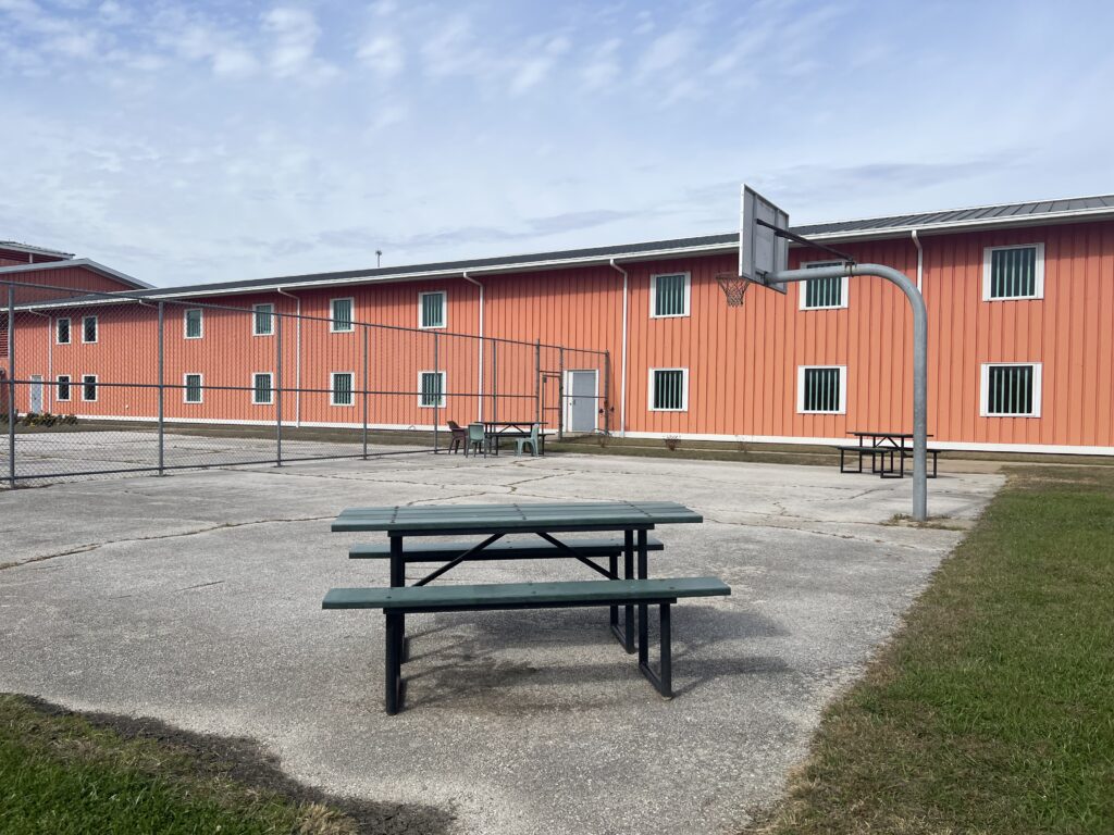 Fenced yard with basketball hoop and picnic tables