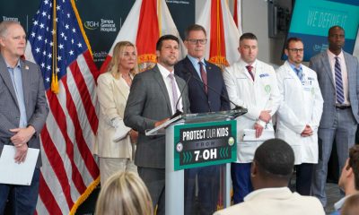 Officials and doctors at podium with U.S. flags