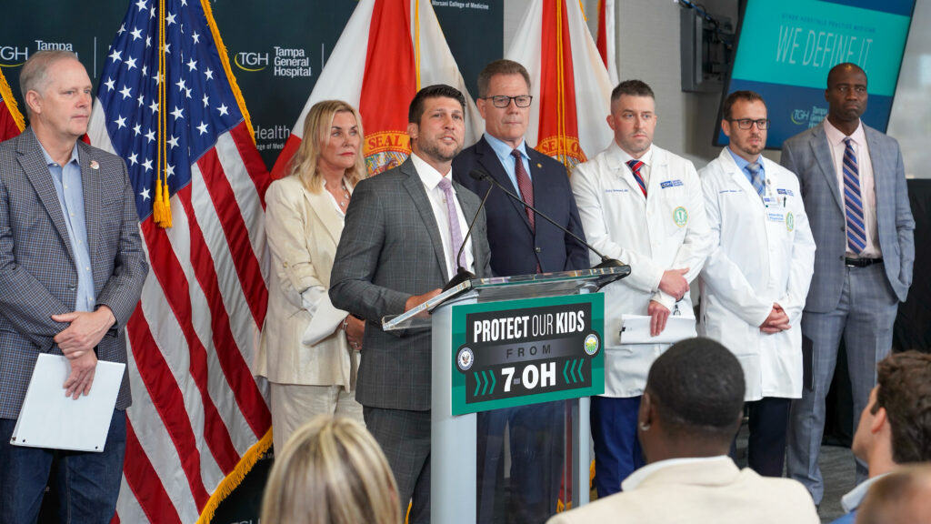 Officials and doctors at podium with U.S. flags