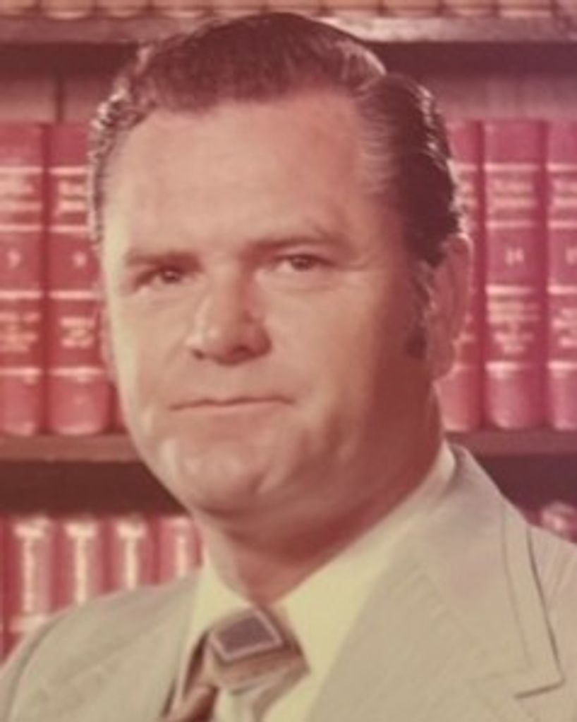 Portrait of man in suit before bookshelves
