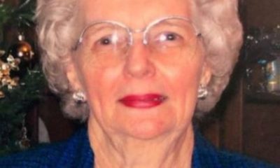 Elderly woman with white hair and glasses smiling