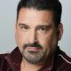 Headshot of man with goatee in maroon jacket
