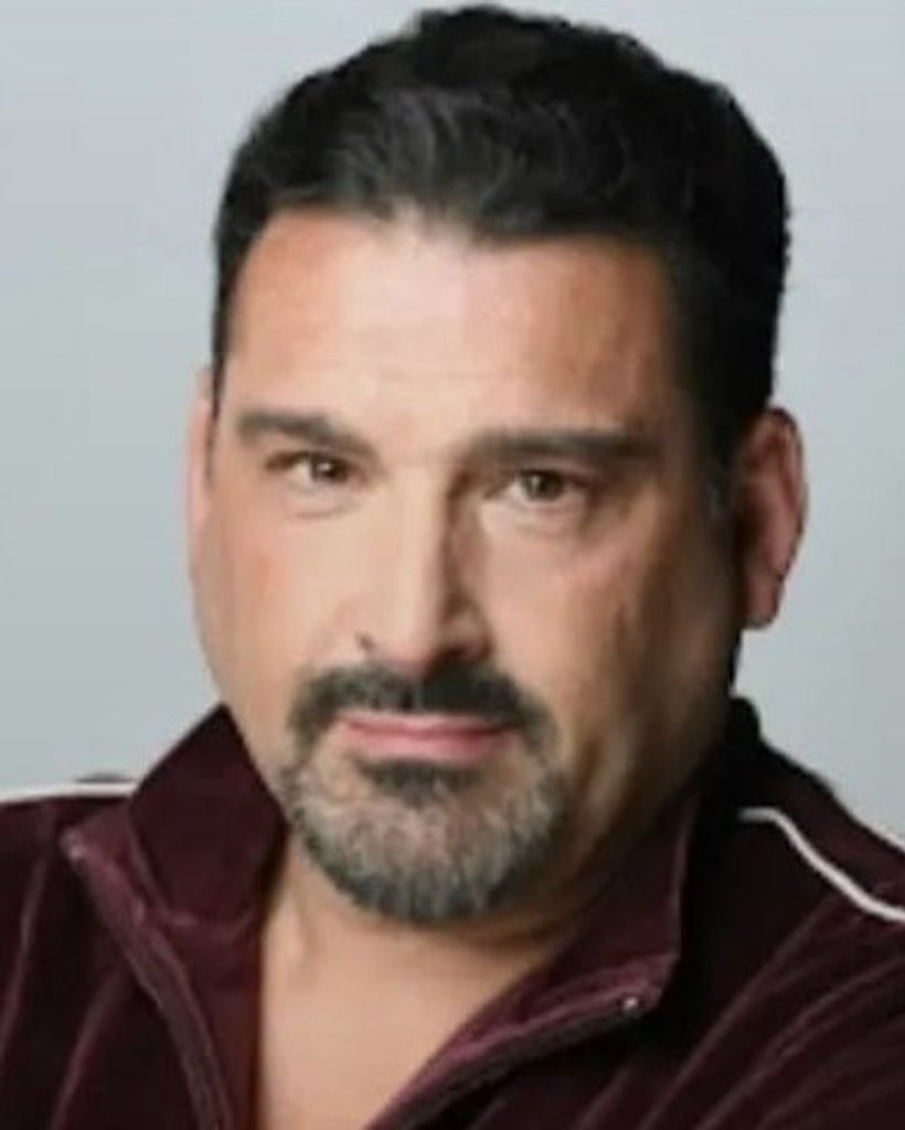 Headshot of man with goatee in maroon jacket