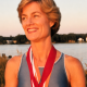 Smiling athlete wearing medals by lakeside at sunset