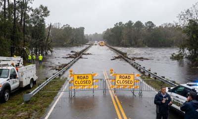 Flooded bridge with road closed signs and emergency crews