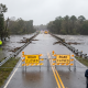 Flooded bridge with road closed signs and emergency crews