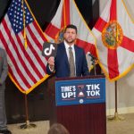 Man holds TikTok logo at press conference podium — Florida TikTok lawsuit minors — Demanda contra TikTok en Florida