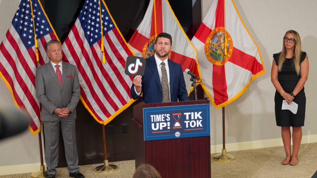 Man holds TikTok logo at press conference podium