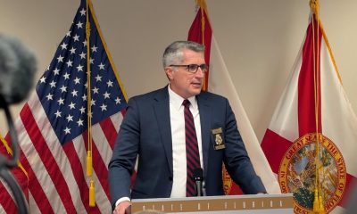 Official speaking at podium with U.S. and Florida flags