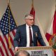Official speaking at podium with U.S. and Florida flags