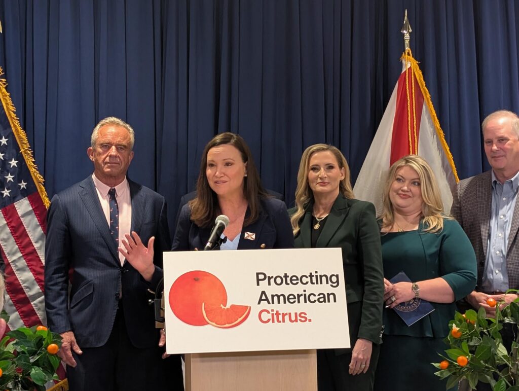 Officials at podium promoting American citrus protection