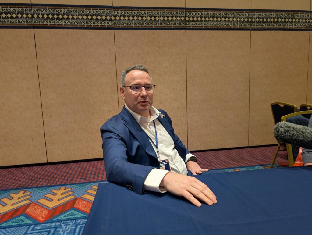 Man in blue suit seated at conference table