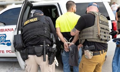 Police officers arrest man beside patrol vehicle
