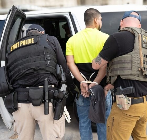 Police officers arrest man beside patrol vehicle
