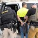 Police officers arrest man beside patrol vehicle
