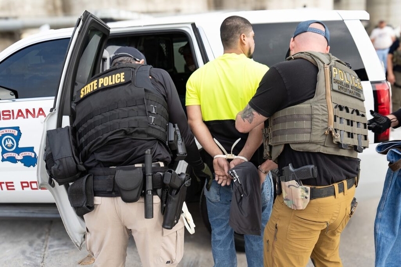 Police officers arrest man beside patrol vehicle