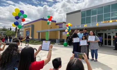 Family posing with certificates outside school building